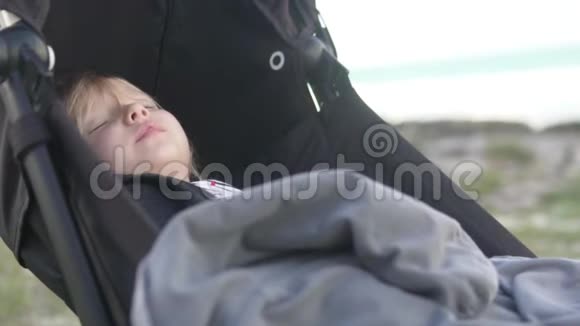 一个小女孩睡在海滩上的婴儿车里视频的预览图