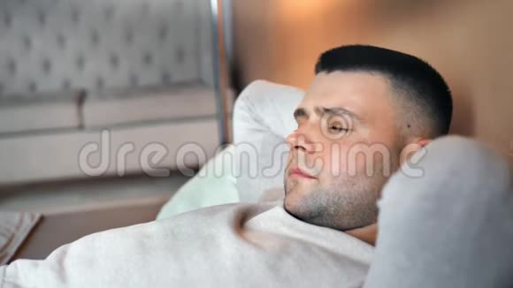 近距离疲惫的白种人躺在床上闭着眼睛试图睡在柔软的枕头上视频的预览图