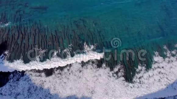 波浪在礁石鸟瞰图上滚动巴厘岛海岸附近的珊瑚礁在清澈蔚蓝的海水下视频的预览图