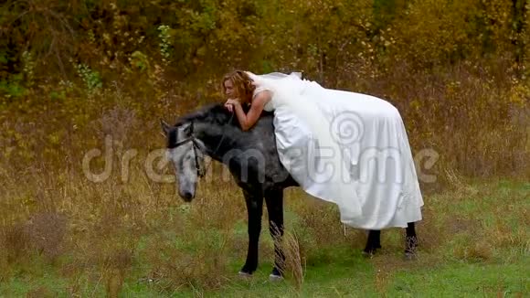 新娘穿着白色婚纱坐在马背上吃东西视频的预览图