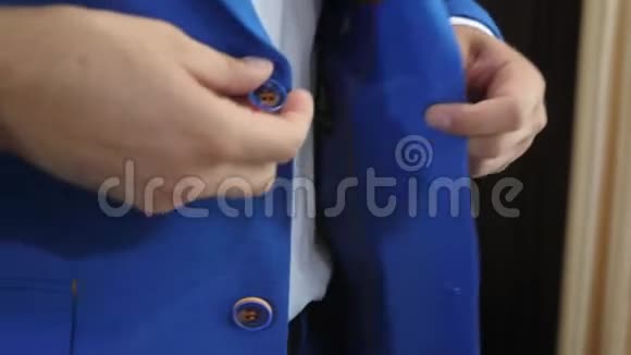 时髦男人把扣子系在蓝色夹克上特写镜头穿西装的时髦男人把扣子系在夹克上准备视频的预览图