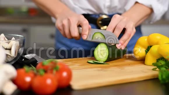 女人慢慢地在厨房的切板上切黄瓜视频的预览图