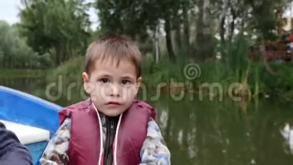 小可爱的孩子拿着桨的肖像近距离观看小可爱男孩在湖上对着镜头微笑快乐的孩子抱着爸爸视频的预览图