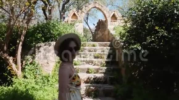 迷人的女人戴着夏帽和太阳镜漫步在古城的历史景观中关闭后方视野视频的预览图