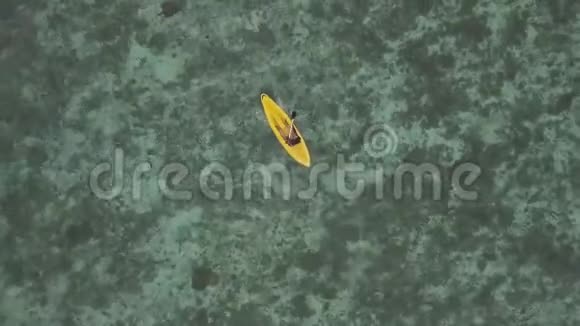 鸟瞰图一名女子在turqouise海水中划独木舟的无人机镜头视频的预览图