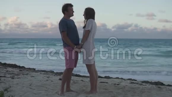 一个男人和一个美丽的女人牵着手互相看着轻轻地亲吻着大海视频的预览图