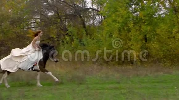 红发未婚妻穿着婚纱骑着奔驰的马在木头附近视频的预览图