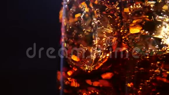 冰和泡泡的可乐4K慢动作的黑色背景上有冰块旋转的冷可乐杯视频的预览图