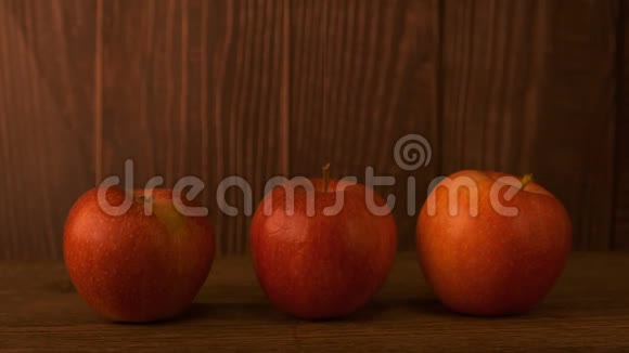 桌子上有三个红苹果放在木板的背景下视频的预览图