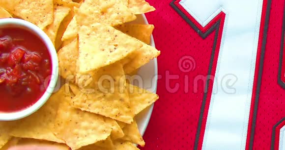 人们在一件19号和足球的红色球衣上吃带有温和萨尔萨的有机玉米片视频的预览图