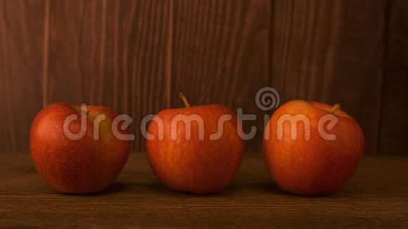 桌子上有三个红苹果放在木板的背景下视频的预览图