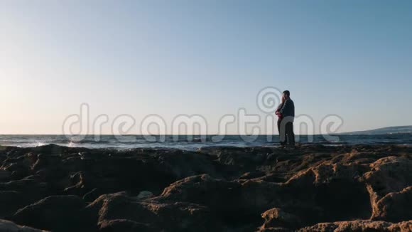 恋爱中的年轻夫妇站在海滨拥抱浪漫的年轻夫妇站在海边拥抱恋爱中的一对美丽的情侣视频的预览图