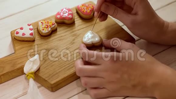 用糖霜装饰姜饼的过程女人的双手为情人节装饰心形饼干视频的预览图