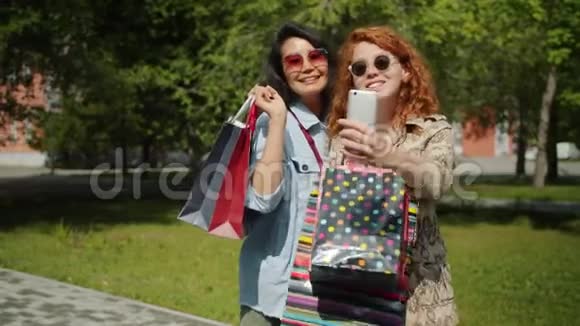 年轻女士在公园户外用手机用购物袋自拍视频的预览图