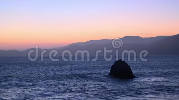在海洋上空的地平线后一个夕阳在岩石周围飞翔的海鸟在放松视频的预览图