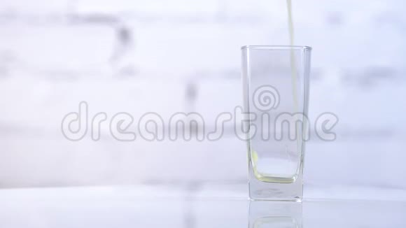 鲜榨橙汁倒在桌子上的玻璃杯里白色背景上清爽的黄色饮料视频的预览图