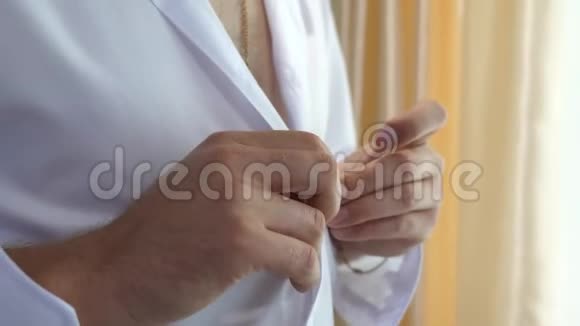 男人的手把扣子系在白色衬衫上一个人早上穿上衣服去上班办公室工作人员年轻的商人视频的预览图