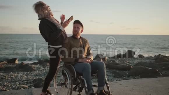 男性轮椅使用者和他的女性朋友通过智能手机自拍视频的预览图