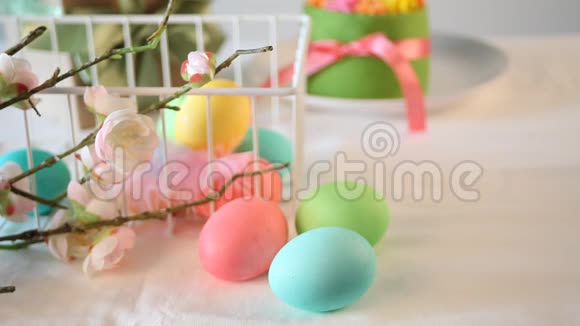 春季复活节节日餐桌背景上有黄油奶油花和五颜六色的鸡蛋的小绿色蛋糕女人的手视频的预览图
