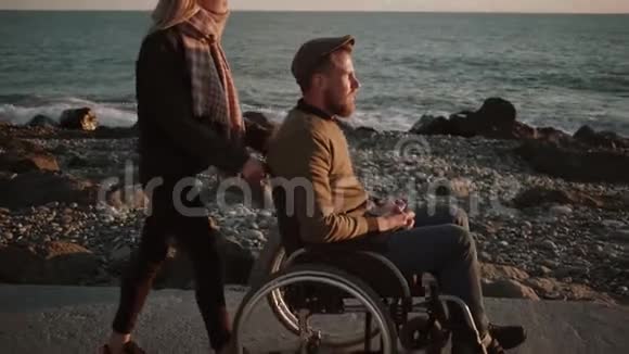 照顾残疾丈夫和他一起在海边散步的女人视频的预览图