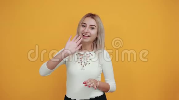 穿着白色衬衫的漂亮时髦女人把空气吻放在橙色墙边视频的预览图