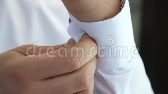 年轻的商人去参加一个商务会议男人的手把扣子系在白衬衫袖子上男人穿上视频的预览图