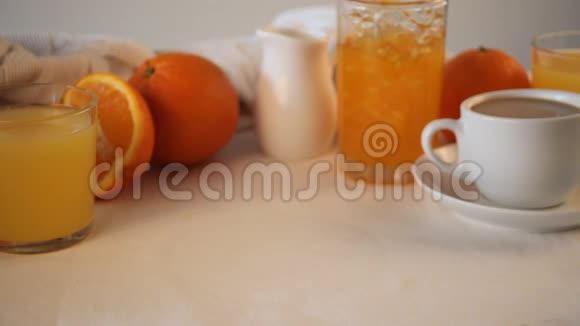 女人的手在桌子上放了一个盘子上面放着新鲜的羊角面包附近有橘子橘子果酱和果汁早餐概念视频的预览图