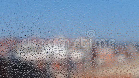 有水滴纹理的雾状玻璃窗背景是模糊的建筑物视频的预览图