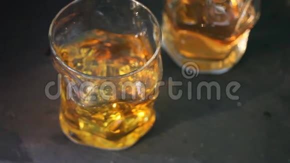 黑桌上放两杯加冰的威士忌冰落在玻璃里视频的预览图