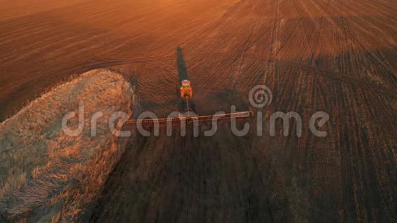 春田工作拖拉机在夕阳下耕耘土地空中视频视频的预览图