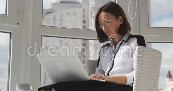 专注的年轻商务女性穿着严格的衣服厌倦了在办公室工作摘下眼镜关闭笔记本电脑女人头疼视频的预览图