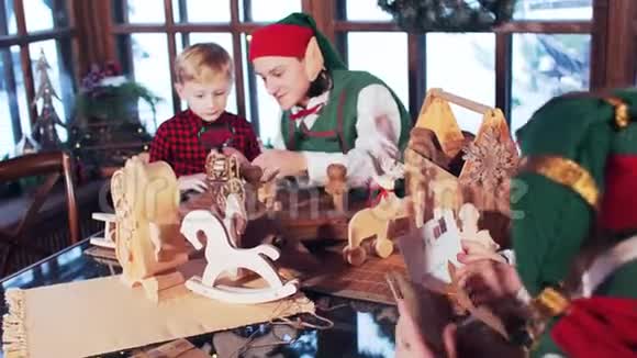 一个穿红色衬衫的男孩和一个圣诞精灵玩木玩具视频的预览图