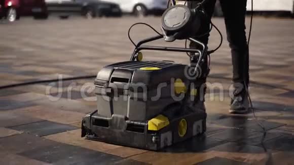 看门人使用手动电动推式清扫车用湿热压垫圈清扫城市人行道铺板视频的预览图