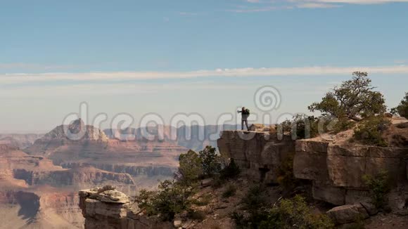 徒步旅行者女人站在大峡谷悬崖边上举起双手跳起来视频的预览图