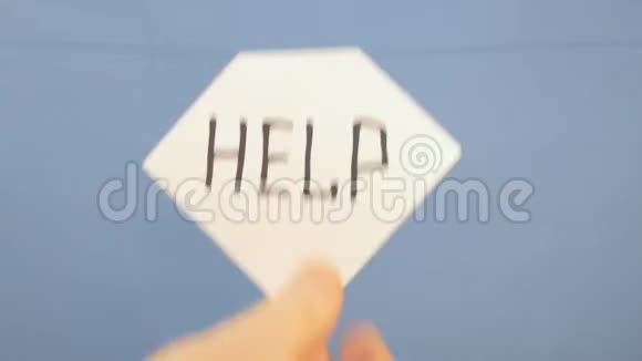 一个男人把一张白纸挂在蓝色的背景上上面有黑色的铭文帮助视频的预览图