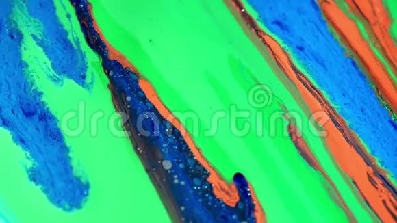 五颜六色的闪闪发光的绿色油漆混合蓝色绿色黄色和其他颜色的油墨在表面展开混合一种视频的预览图
