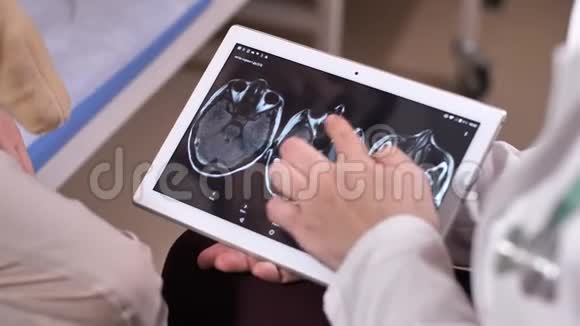 医生拿着平板电脑在屏幕上进行脑部扫描视频的预览图