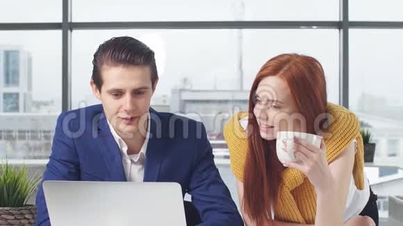 两名年轻的办公室职员在笔记本电脑上工作看晨报视频的预览图