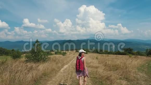 带着红色背包的女旅行者正在山区散步视频的预览图