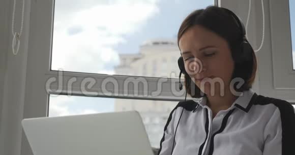 微笑漂亮的女性呼叫中心代理与客户在线通过耳机交谈耳机里的女支持经理视频的预览图