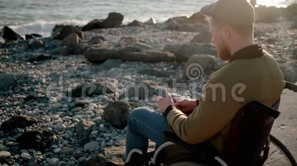 坐在河堤上的男性轮椅使用者通过手机通话视频的预览图