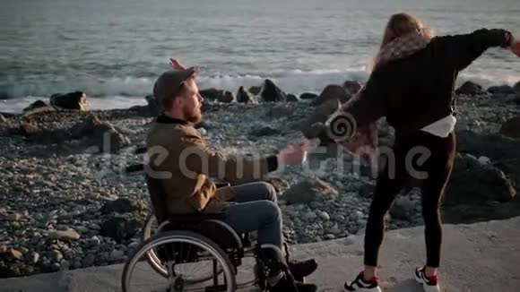 有趣的年轻人在海边跳舞男性轮椅使用者和年轻女士视频的预览图