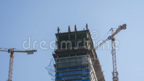 建筑工地上的塔式起重机在高层建筑中提升负荷时光流逝视频的预览图