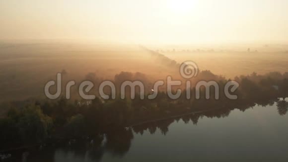 雾蒙蒙的早晨鸟瞰湖面和田野视频的预览图