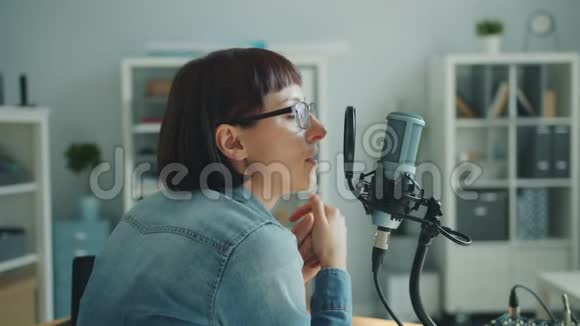 戴眼镜的严肃女人用麦克风为音频博客录音讲话视频的预览图