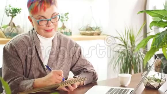 严肃的高级商务女性在笔记本上写工作问题视频的预览图