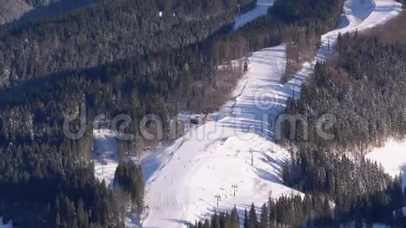 在阳光明媚的一天滑雪者和滑雪者在滑雪场的雪坡上骑在山上视频的预览图