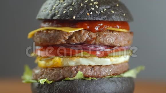 黑汉堡一个汉堡里面有一个黑卷切片多汁的大理石牛肉融合奶酪新鲜沙拉和烤肉酱视频的预览图