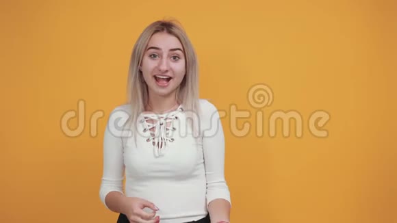 一幅年轻女子在橙色的墙上用拇指向旁边张望的画像视频的预览图