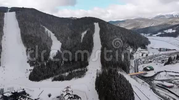 在滑雪胜地设有滑雪者的空中滑雪斜坡雪山森林Bukvel视频的预览图